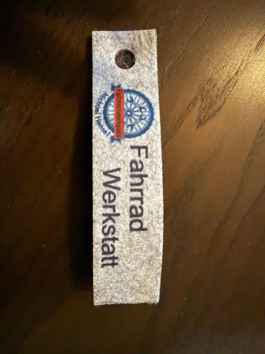 Filz Schlüsselanhänger Schild mit der Aufschrift "Fahrrad Werkstatt" und einem Logo.